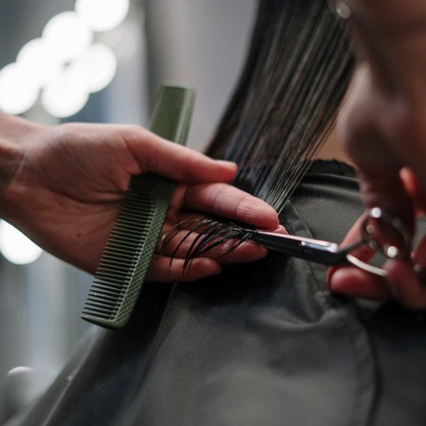 Close-up of hairstylist cutting wet hair in a salon.